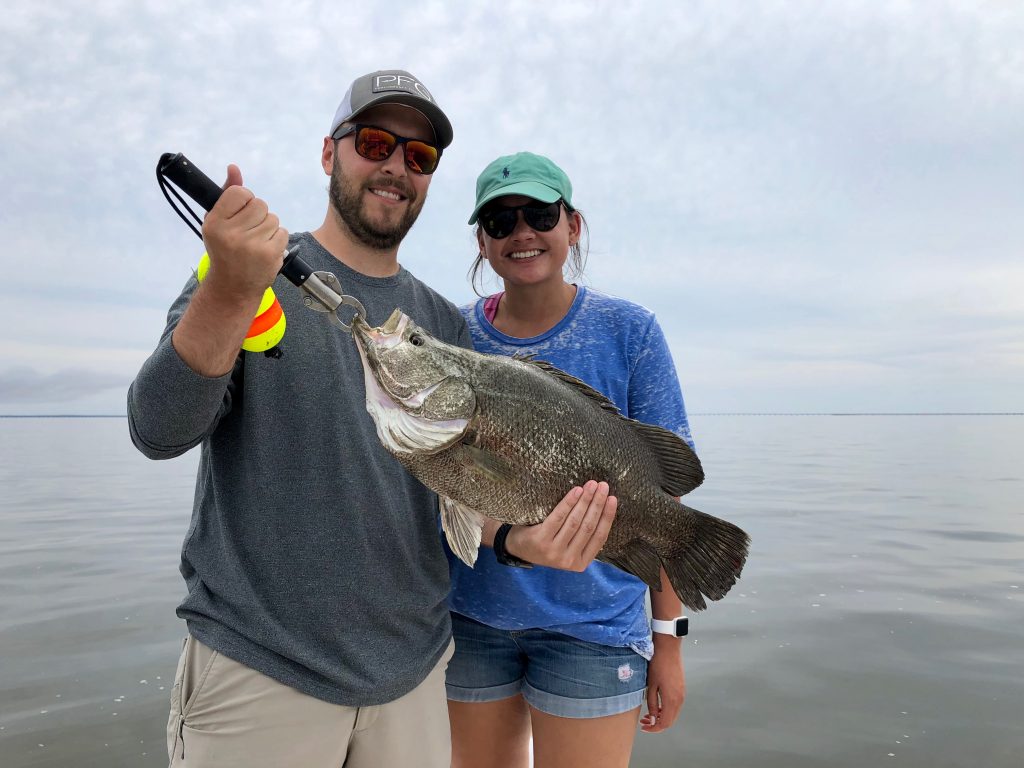 Couple holding triple tail caught on charter